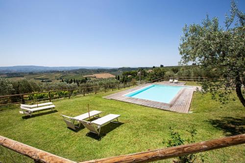 a yard with a swimming pool and two benches at Fattoria Le Fonti in Poggibonsi