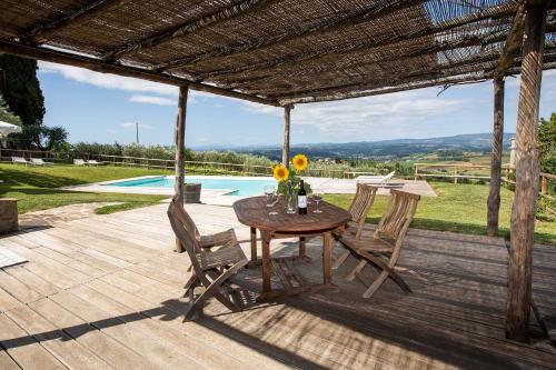 a wooden table and chairs on a patio with a pool at Fattoria Le Fonti in Poggibonsi