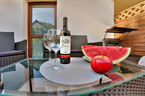 a bottle of wine and an apple on a glass table at Apartmany za Rohom in Liptovský Mikuláš