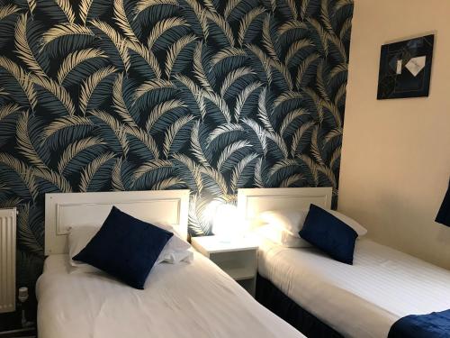 two beds in a room with a wall mural at The Feathers Hotel in Blackpool