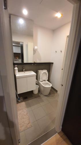 a bathroom with a toilet and a sink and a mirror at Gardenia Apartment an ideal place to relax and enjoy in Clayton North