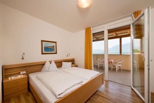 a bedroom with a bed and a balcony with a table at Pensione Penegalblick in Appiano sulla Strada del Vino