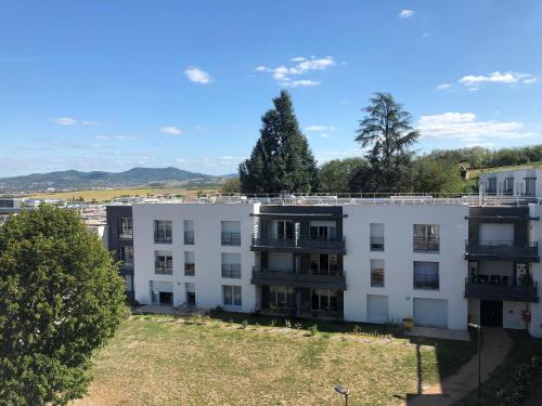 a white apartment building with trees and mountains in the background at Domitys - Le Manoir in Pérignat-lès-Sarliève