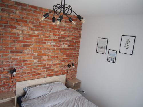 a bedroom with a brick wall and a bed at Nadmorska Ostoja z prywatnym miejscem postojowym in Pogórze