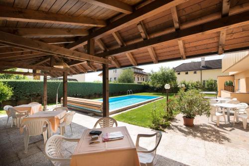 a patio with tables and chairs and a pool at Pensione Penegalblick in Appiano sulla Strada del Vino