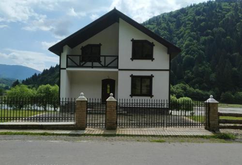 a small white house with a black fence at Котедж Shalet in Kolochava