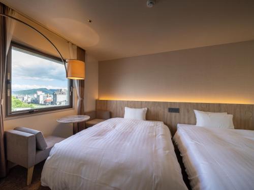 a hotel room with two beds and a window at Hotel Flags Isahaya Nagasaki in Isahaya