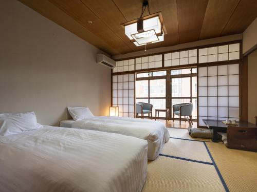a bedroom with two beds and a table and chairs at Hotel Flags Isahaya Nagasaki in Isahaya