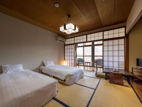 a hotel room with two beds and a television at Hotel Flags Isahaya Nagasaki in Isahaya
