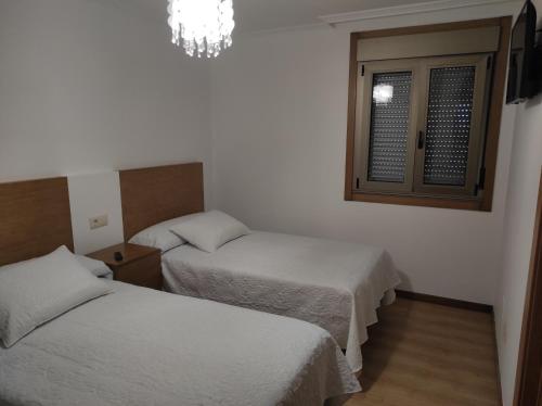 Cette chambre comprend deux lits et un lustre. dans l'établissement O LAR DE SARA II, à Poio