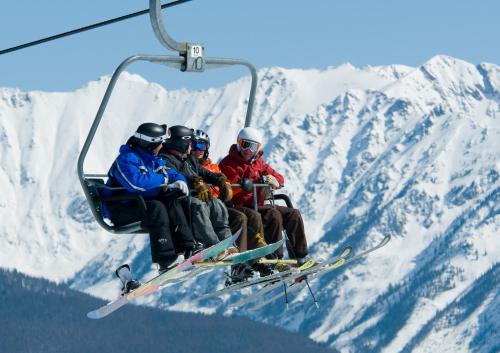 a group of people sitting on a ski lift at The Christie Lodge – All Suite Property Vail Valley/Beaver Creek in Avon
