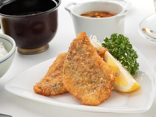 a white plate with two pieces of fish and a lemon at Hotel Flags Isahaya Nagasaki in Isahaya