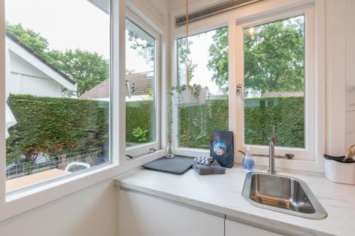 een keuken met twee ramen en een wastafel bij Welcome in - Vakantiewoning met zonnige tuin, dichtbij zee en strand I Noordendolfer 2-49 in Zoutelande