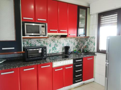 Una cocina con gabinetes rojos y un microondas. en El Balcón de Luán, en Suances