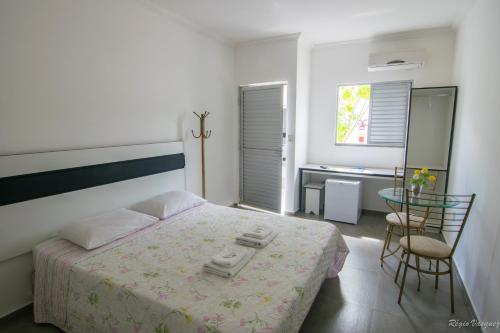 a bedroom with a bed with a table and chairs at Hotel Caraipe in Teixeira de Freitas