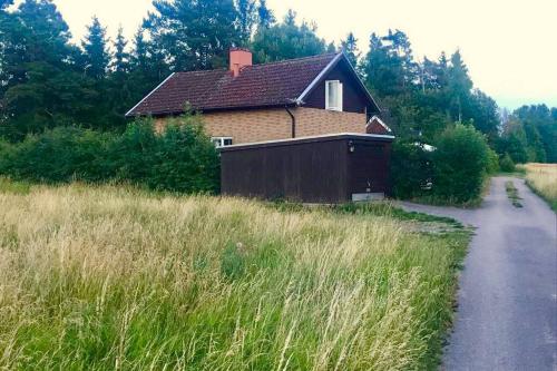 a house in a field next to a road at The Cozy Little House in Motala