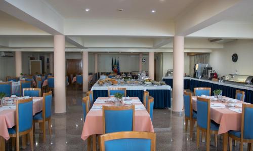 un salón de banquetes con mesas azules y sillas azules en Hotel Sao Jorge Garden en Velas