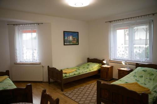 a bedroom with two beds and two windows at Dom Pod Lipą in Rymanów-Zdrój