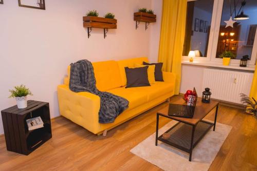 sala de estar con sofá amarillo y mesa en Apartament Słoneczny, en Zbąszyń