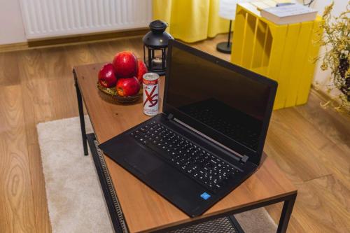a laptop computer on a table with a bowl of apples at Apartament Słoneczny in Zbąszyń