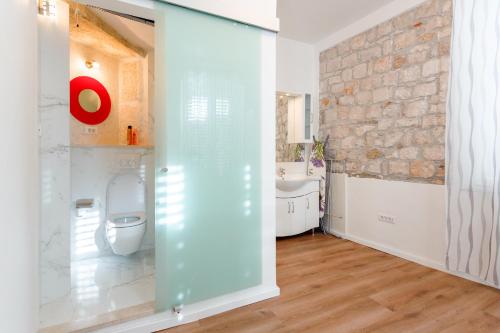 a bathroom with a toilet and a stone wall at Apartments Fortezza in Split