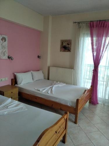 a bedroom with two beds and a window at Poseidon rooms in Nea Vrasna