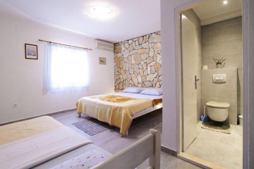 a bedroom with a bed and a stone wall at Apartments Uskok in Vis