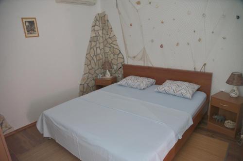 a bedroom with a white bed and two night stands at Apartments Uskok in Vis