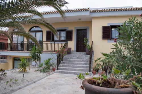 una casa con escaleras y palmeras delante en Vivienda Vacacional TINIZARA, en Arona