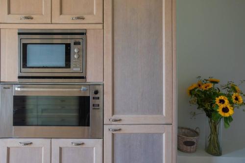 a kitchen with a microwave and a vase of flowers at Villa Eternity, Ai Helis Kefalonia in Kefallonia
