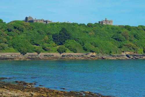 a body of water with a hill with trees and a castle at Chy Bre in Truro