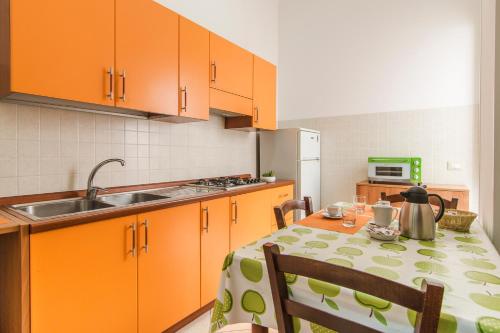 une cuisine avec des armoires orange et une table avec un chiffon de table dans l'établissement Galatea appartamento grande, à Pozzallo