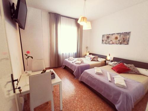 ein Hotelzimmer mit 2 Betten und einem Tisch in der Unterkunft Luce in Lucca