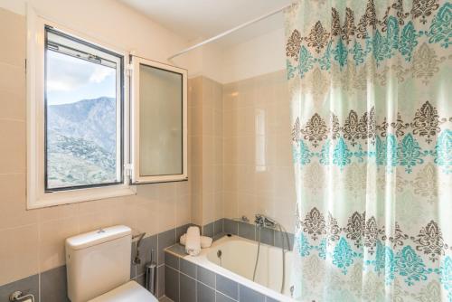 a bathroom with a tub and a toilet and a window at Villa Frati Gorge in Fratíon