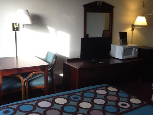 a hotel room with a bed and a desk with a microwave at Super 8 by Wyndham Kennett in Kennett