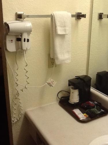 a bathroom with a sink and a hair dryer on a counter at Super 8 by Wyndham Kennett in Kennett
