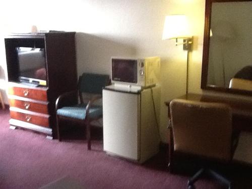 a hotel room with a refrigerator and a tv at Super 8 by Wyndham Kennett in Kennett