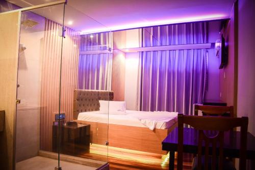 - une chambre dotée d'un lit avec des lumières violettes dans l'établissement Motel Sunny Day Contagem, à Contagem