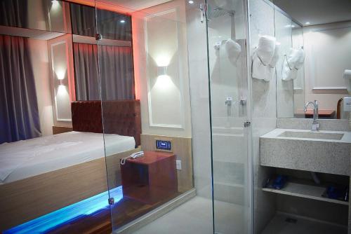 baño con ducha, cama y lavamanos en Motel Sunny Day Contagem en Contagem
