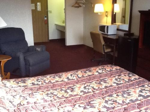 a hotel room with a bed and a chair and a desk at Super 8 by Wyndham Kennett in Kennett