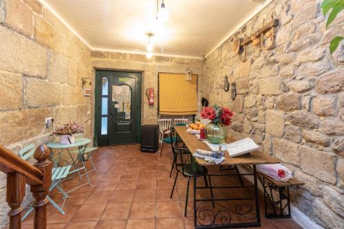 a room with a stone wall with a table and chairs at Albergue Casa de Abreu in Redondela