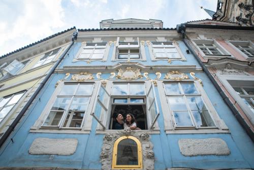 a woman standing in the window of a blue building at Charles Bridge Hostel & Apartments in Prague