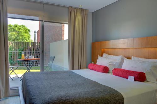 1 dormitorio con 1 cama grande con almohadas rojas en Rambla Apartamentos, en Montevideo