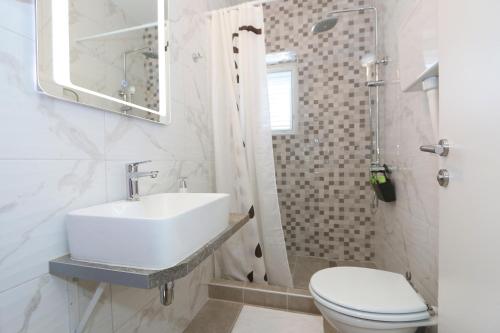 a white bathroom with a sink and a toilet at Rooms Bambina in Lun