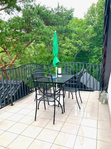 a table and chairs with a green umbrella on a balcony at Willa 4 Pory Roku & Uznam in Świnoujście