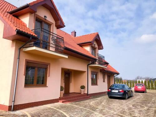 a house with two cars parked in a driveway at Pokoje z łazienkami - DZIWNÓWEK in Kamień Pomorski