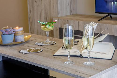 a table with two glasses of wine and a book at Savvas Apartment in Tolo