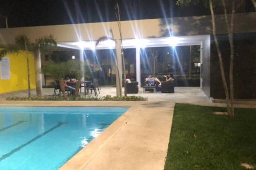 una piscina por la noche con gente sentada en una mesa en La Llar que deseas para vacacionar., en Cancún