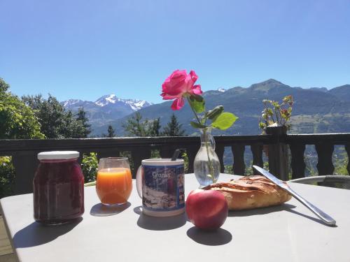 a table with a plate of food and a vase with a rose at Maison de l'Epine -spa- Versant du soleil in Granier