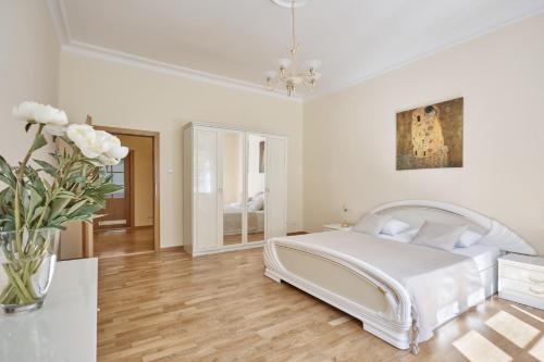 - une chambre blanche avec un lit et un vase de fleurs dans l'établissement Villa Deluxe Apartments, à Karlovy Vary